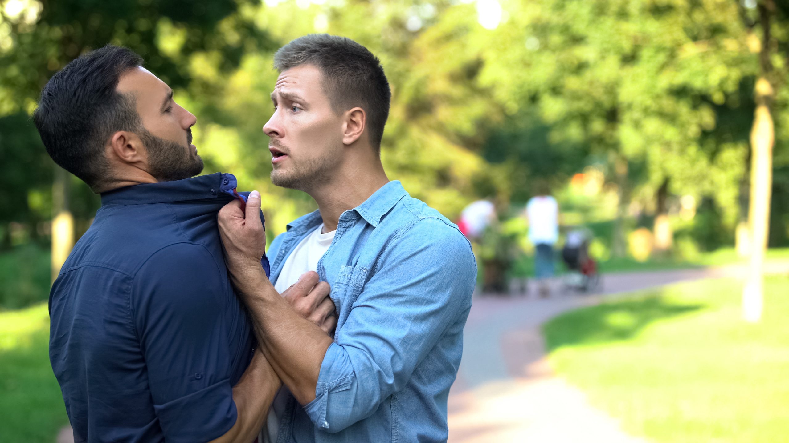 Angry man pushing threatening male outdoors solving problem force, aggression